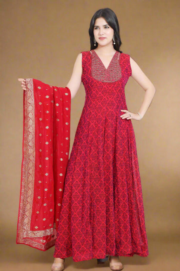 Woman wearing a red patterned dress with a matching dupatta, standing indoors.