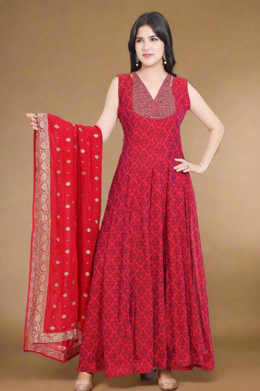 Woman wearing a red patterned dress with a matching dupatta, standing indoors.